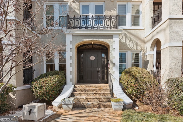 property entrance featuring a balcony and stucco siding