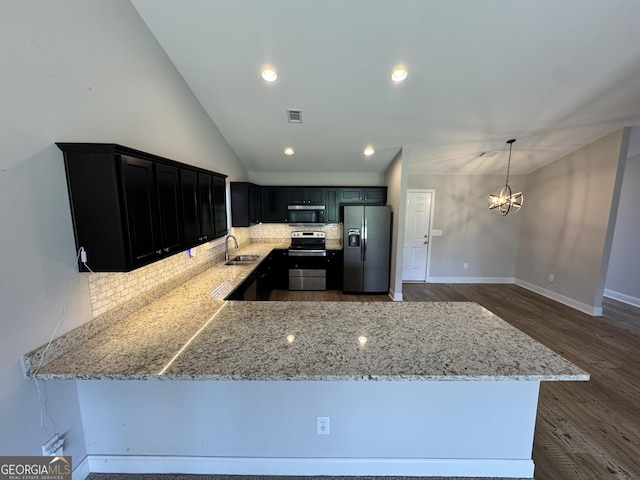 kitchen featuring a sink, a notable chandelier, appliances with stainless steel finishes, decorative backsplash, and light stone counters
