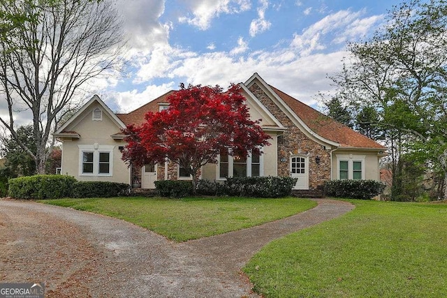 view of front of home with stucco siding, stone siding, and a front yard