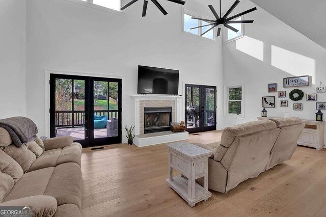 3060 Cabernet Ct, Cumming, GA 30041 - living room featuring french doors, a towering ceiling, a ceiling fan, light wood-style floors, and a fireplace