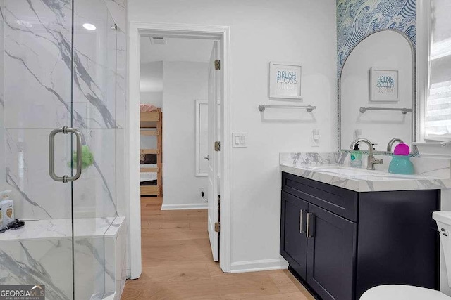 full bathroom with wood finished floors, a marble finish shower, vanity, baseboards, and visible vents