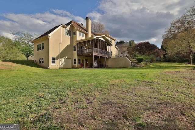 back of house featuring a chimney, a wooden deck, a yard, and stucco siding