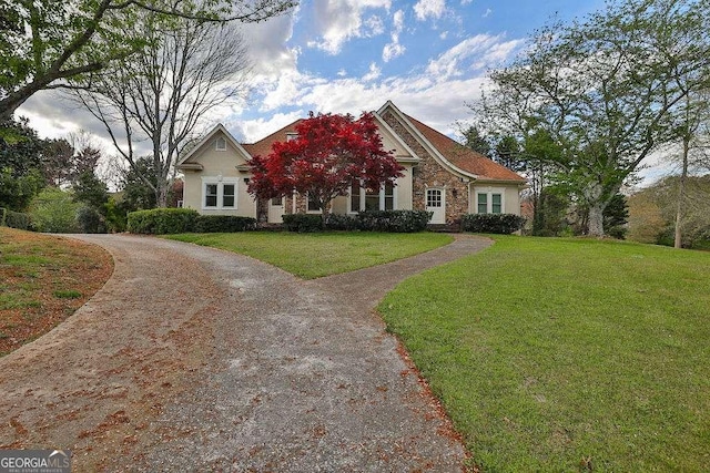 view of front of property with stucco siding, stone siding, and a front yard