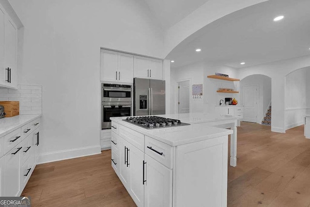 kitchen featuring arched walkways, open shelves, stainless steel appliances, and recessed lighting