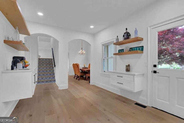 interior space featuring arched walkways, light wood finished floors, baseboards, visible vents, and recessed lighting