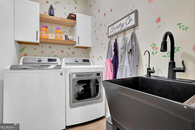 laundry area featuring washer and dryer, a sink, wallpapered walls, and cabinet space