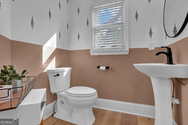 bathroom with wood finished floors, baseboards, and toilet
