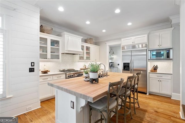 4675 Lakeway Pl, Alpharetta, GA 30005 - kitchen with crown molding, wood counters, tasteful backsplash, built in appliances, and custom range hood