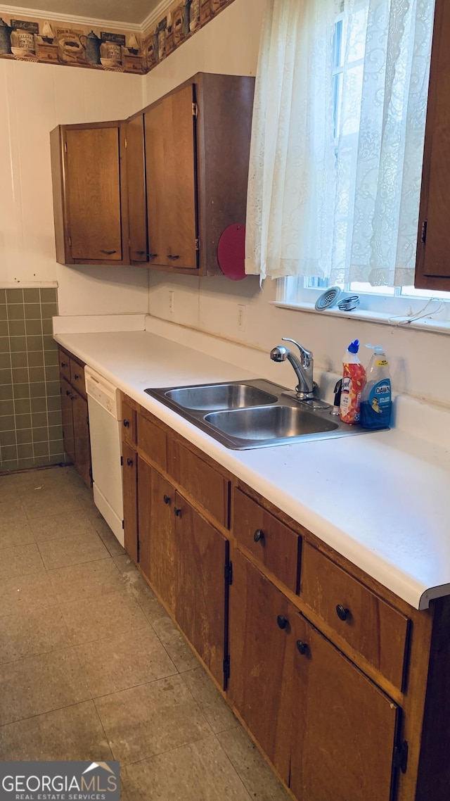 kitchen featuring dishwasher, brown cabinets, a sink, and light countertops