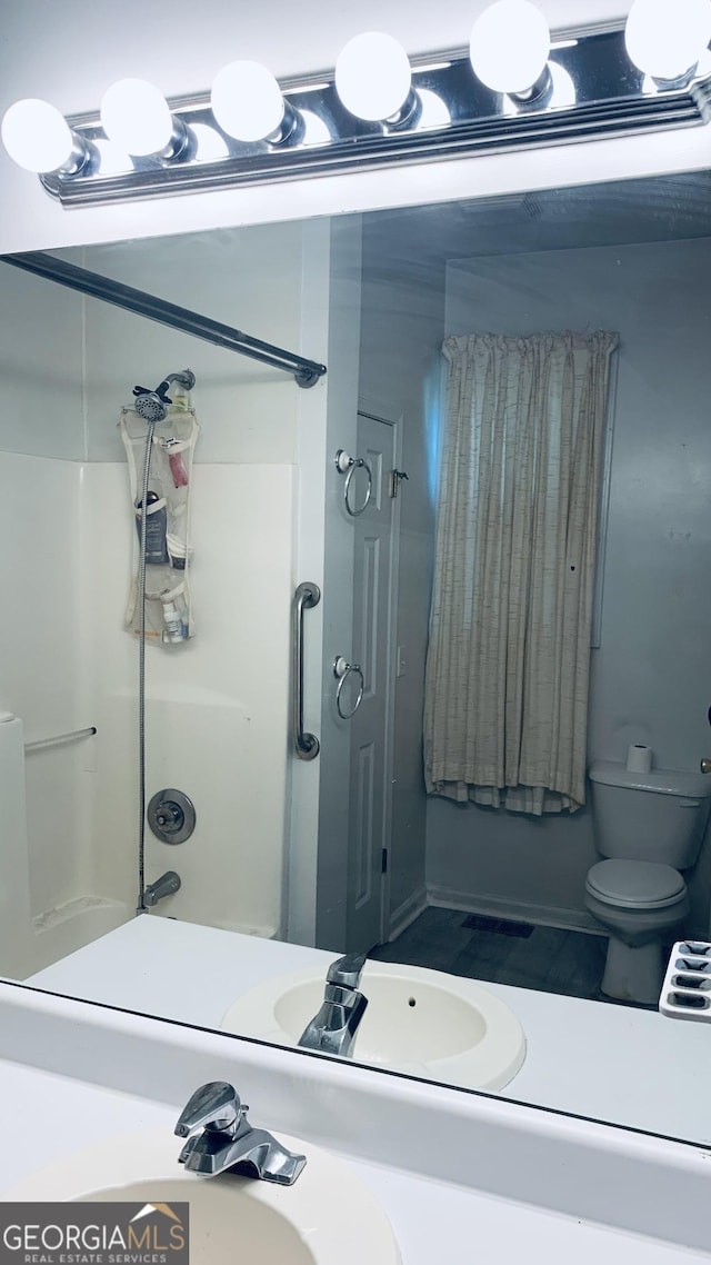 bathroom featuring walk in shower, a sink, and toilet