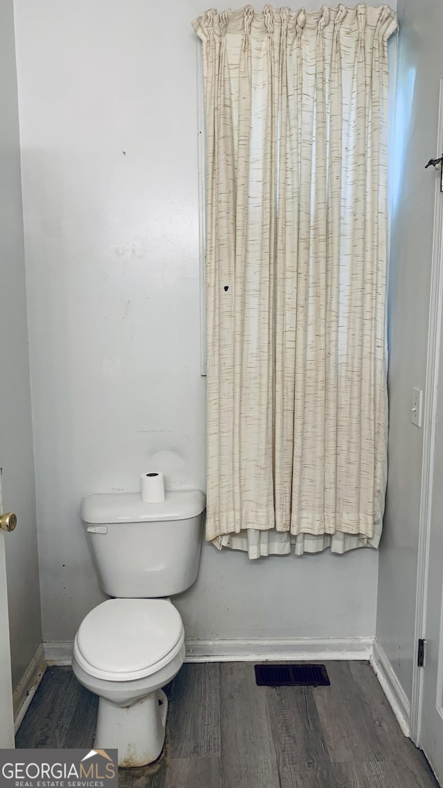 bathroom with wood finished floors, visible vents, toilet, and baseboards