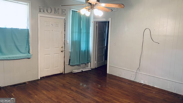 foyer with wood walls, a ceiling fan, and dark wood-style floors