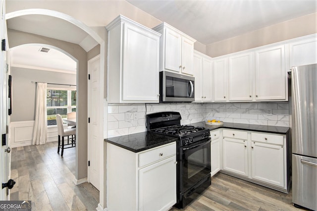 4440 Spring Mtn Ln, Powder Springs, GA 30127 - kitchen featuring stainless steel appliances, arched walkways, light wood-type flooring, dark countertops, and white cabinets