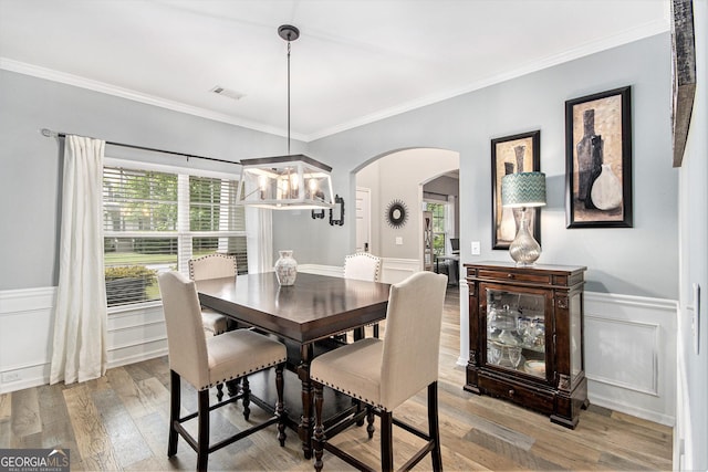 4440 Spring Mtn Ln, Powder Springs, GA 30127 - dining space featuring arched walkways, a chandelier, light wood-style flooring, ornamental molding, and a wainscoted wall