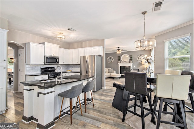 4440 Spring Mtn Ln, Powder Springs, GA 30127 - kitchen with arched walkways, appliances with stainless steel finishes, dark countertops, ceiling fan with notable chandelier, and a sink