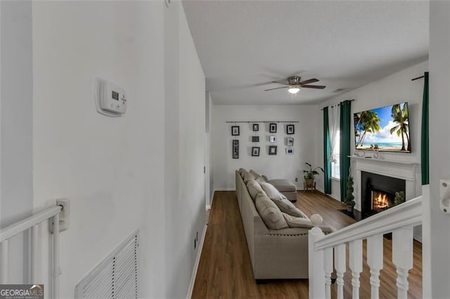 831 Kendall Park Dr, Winder, GA 30680 - living area featuring wood finished floors, ceiling fan, and a warm lit fireplace
