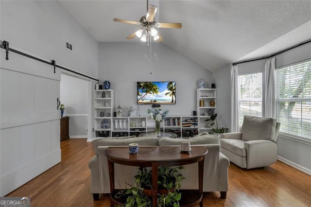 831 Kendall Park Dr, Winder, GA 30680 - living area with a barn door, lofted ceiling, wood finished floors, ceiling fan, and baseboards