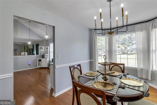 831 Kendall Park Dr, Winder, GA 30680 - dining area featuring a chandelier, wood finished floors, lofted ceiling, a textured ceiling, and baseboards