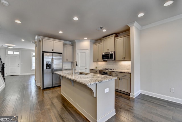 kitchen with tasteful backsplash, a sink, a breakfast bar area, stainless steel appliances, and ornamental molding