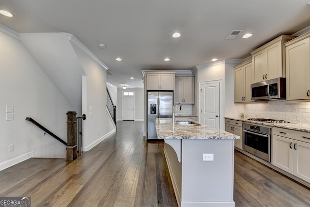 kitchen featuring stainless steel appliances, a sink, tasteful backsplash, visible vents, and light stone countertops