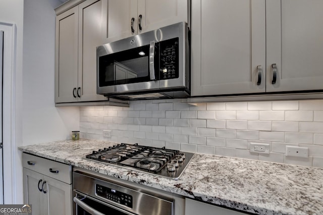 kitchen with tasteful backsplash, light stone countertops, and stainless steel appliances
