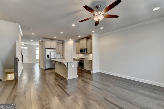 kitchen featuring a sink, appliances with stainless steel finishes, ceiling fan, crown molding, and a breakfast bar area