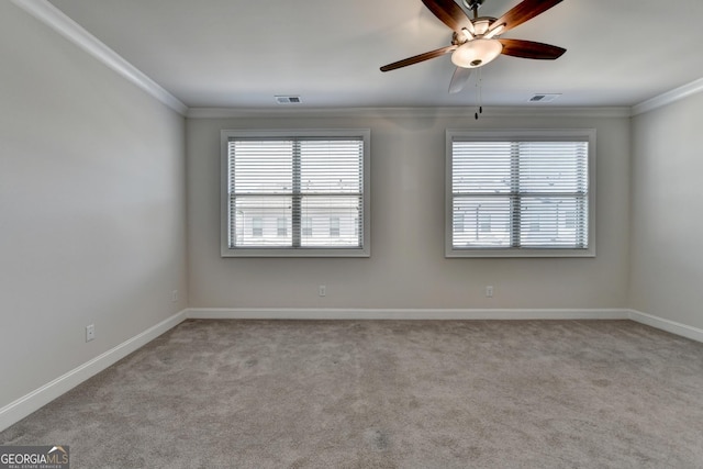 carpeted spare room with a ceiling fan, baseboards, ornamental molding, and visible vents