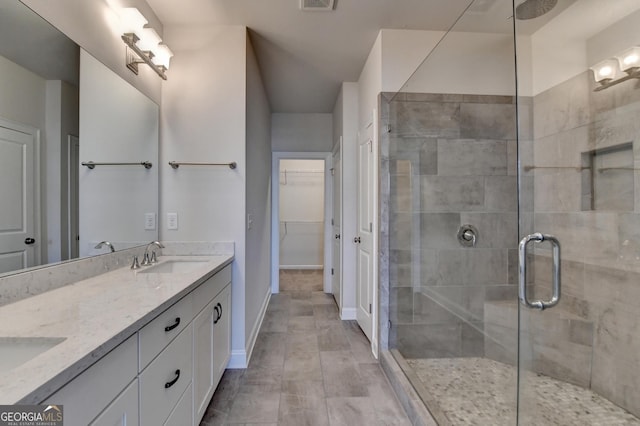 full bathroom with a shower stall, a sink, double vanity, baseboards, and visible vents