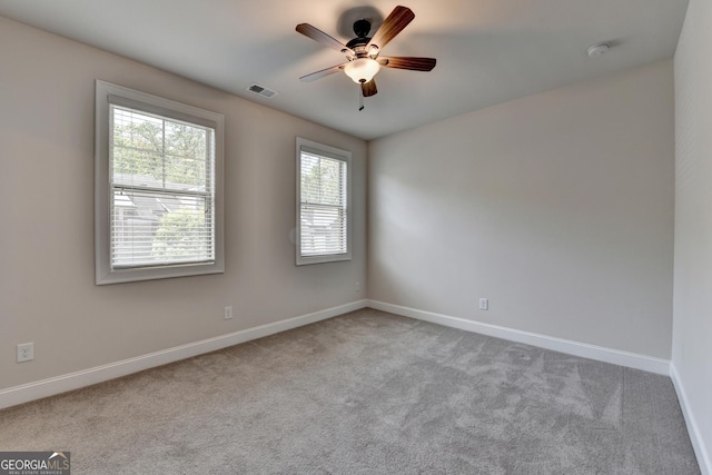 carpeted empty room featuring visible vents, baseboards, and ceiling fan