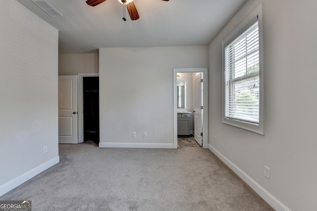 unfurnished bedroom featuring ensuite bath, carpet floors, visible vents, and baseboards