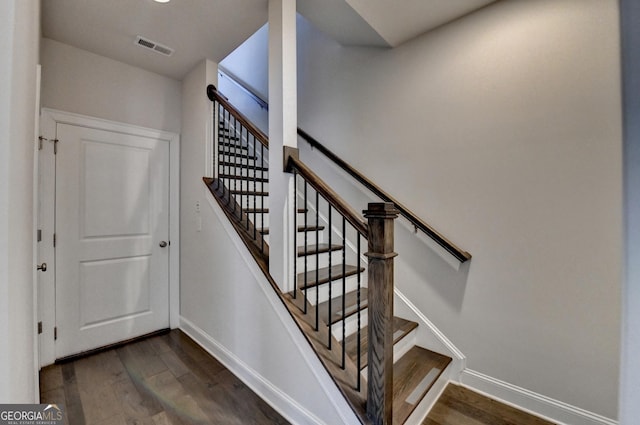 staircase with baseboards, wood finished floors, and visible vents