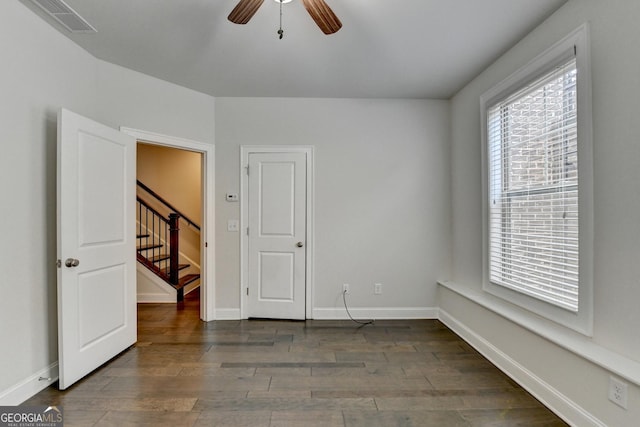 empty room featuring visible vents, baseboards, a ceiling fan, wood finished floors, and stairway