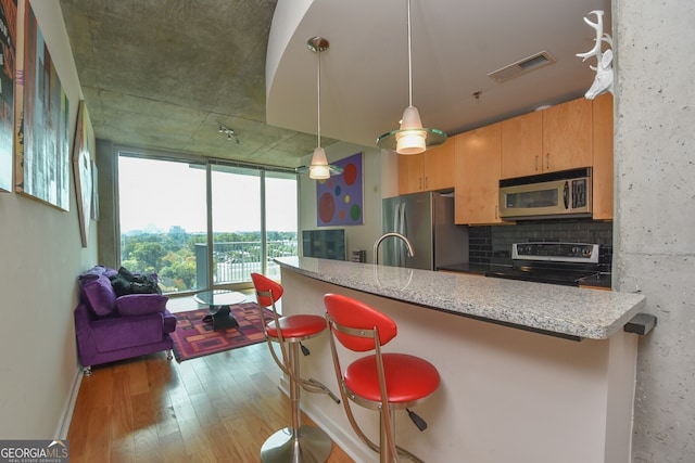 361 17th St NW Unit 1107, Atlanta, GA 30363 - kitchen with stainless steel appliances, light wood-style floors, a kitchen bar, and decorative light fixtures