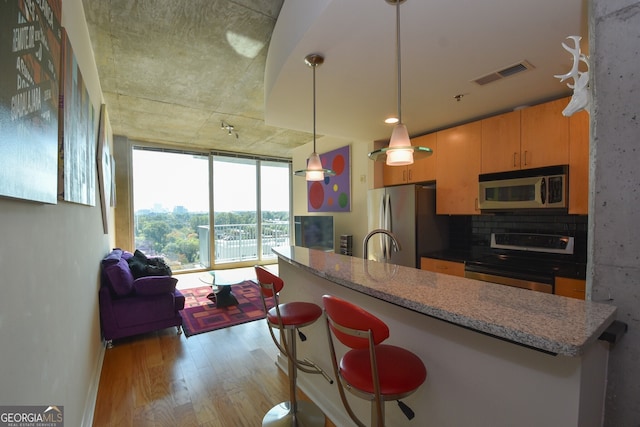 361 17th St NW Unit 1107, Atlanta, GA 30363 - kitchen featuring stainless steel appliances, light wood-style flooring, tasteful backsplash, pendant lighting, and light stone countertops