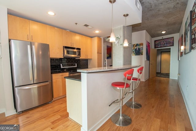 361 17th St NW Unit 1107, Atlanta, GA 30363 - kitchen with appliances with stainless steel finishes, light wood-style floors, a breakfast bar, backsplash, and recessed lighting