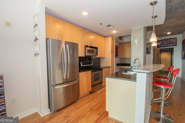 361 17th St NW Unit 1107, Atlanta, GA 30363 - kitchen featuring appliances with stainless steel finishes, light wood-style floors, backsplash, a kitchen bar, and hanging light fixtures