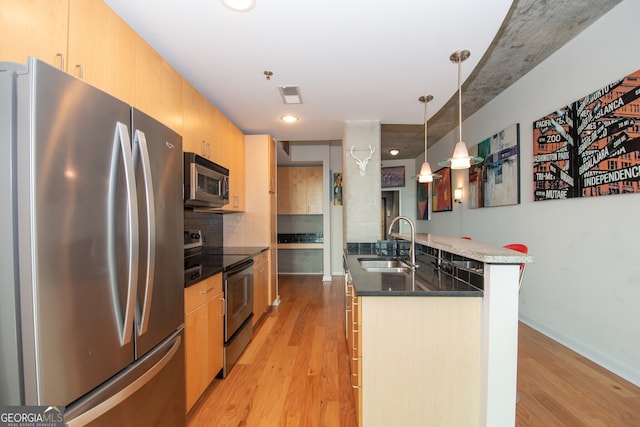361 17th St NW Unit 1107, Atlanta, GA 30363 - kitchen with appliances with stainless steel finishes, light wood finished floors, tasteful backsplash, hanging light fixtures, and dark stone countertops