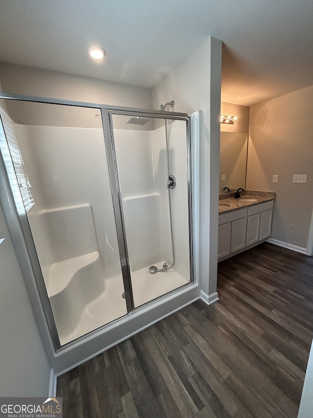 bathroom featuring wood finished floors, a stall shower, baseboards, vanity, and recessed lighting