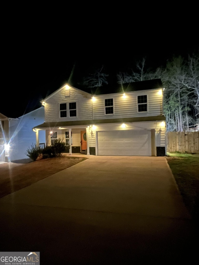 traditional home with an attached garage, driveway, and fence