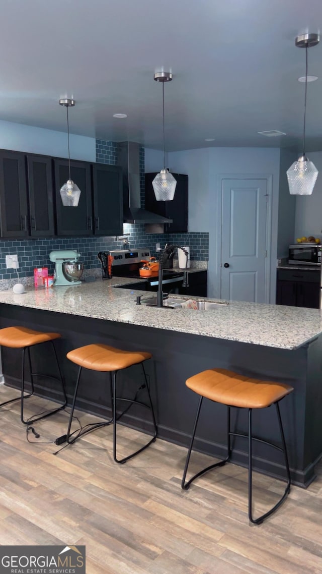 kitchen featuring a kitchen bar, backsplash, light wood-type flooring, and a peninsula