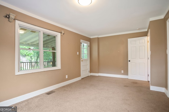 carpeted spare room featuring crown molding, visible vents, and baseboards