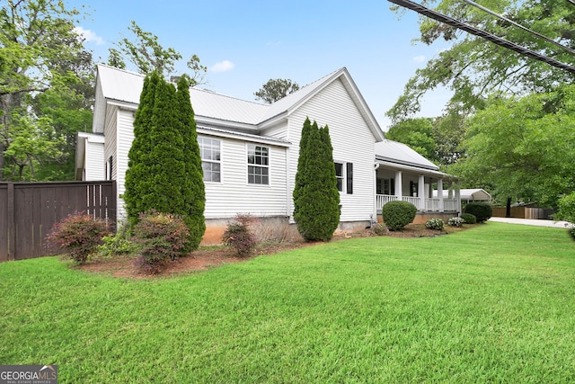 view of property exterior featuring fence, a porch, metal roof, and a yard