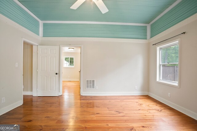 empty room with a wealth of natural light, visible vents, ceiling fan, and wood finished floors