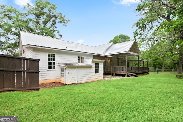 rear view of house with a lawn, fence, metal roof, and a wooden deck