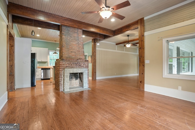 unfurnished living room featuring baseboards, ceiling fan, a fireplace, beam ceiling, and light wood-type flooring