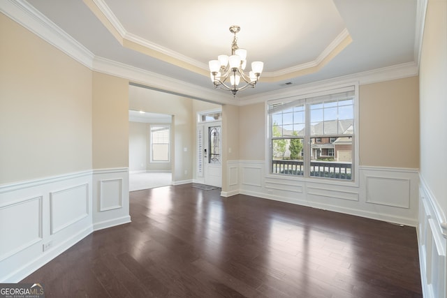 unfurnished dining area with ornamental molding, a notable chandelier, a tray ceiling, and plenty of natural light