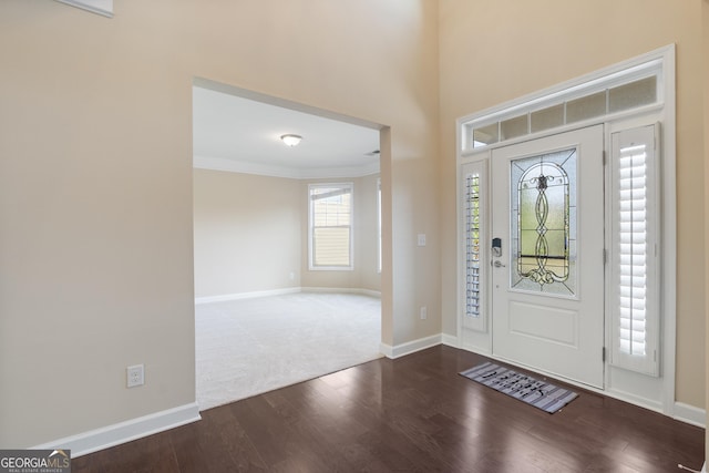 foyer entrance with dark wood finished floors, baseboards, and ornamental molding