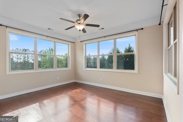 spare room with ceiling fan, baseboards, ornamental molding, and dark wood finished floors