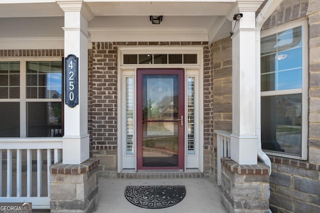view of exterior entry with brick siding and covered porch
