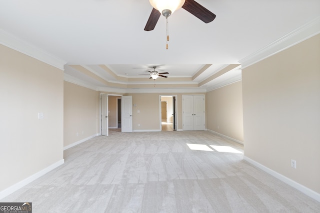 spare room featuring ceiling fan, light carpet, ornamental molding, and a raised ceiling